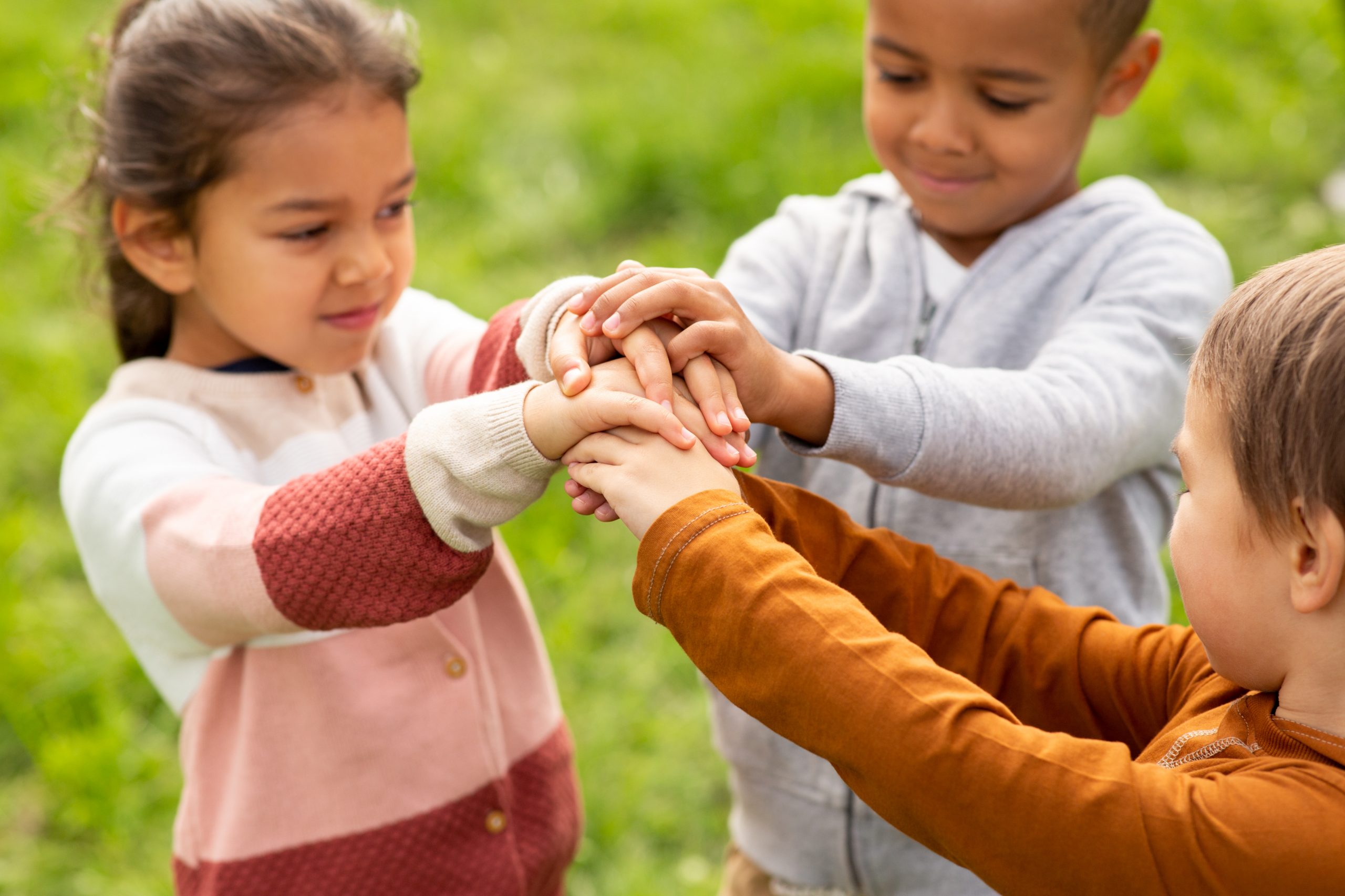 Home group of children stacking hands at park